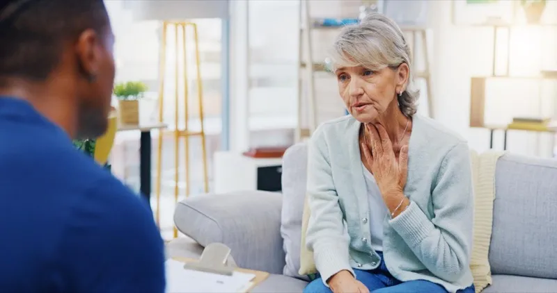 Senior patient consulting with a nurse about swallowing symptoms during a clinical assessment